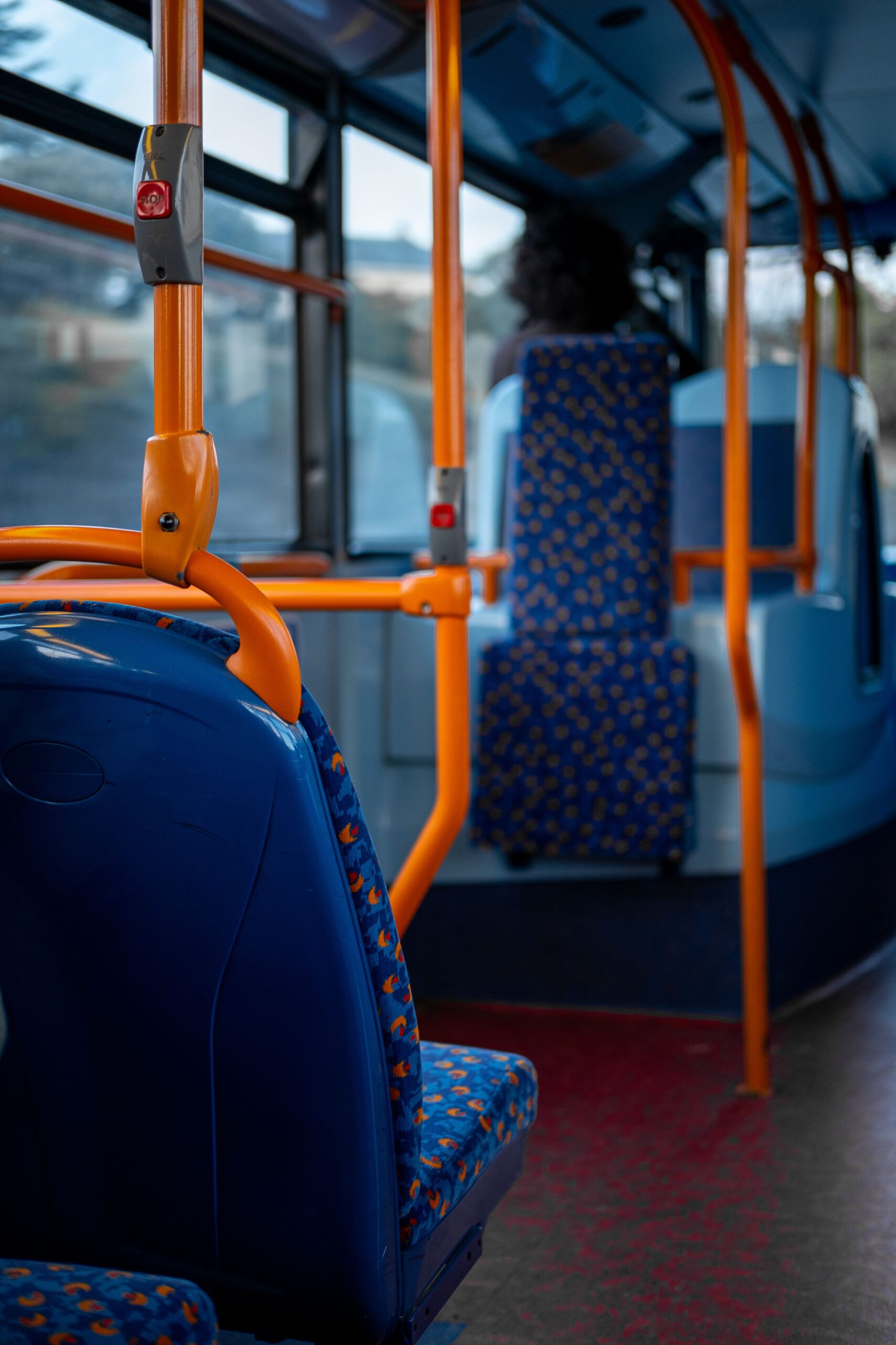 A quiet interior of a public bus with vibrant blue and orange seating, United Kingdom.
